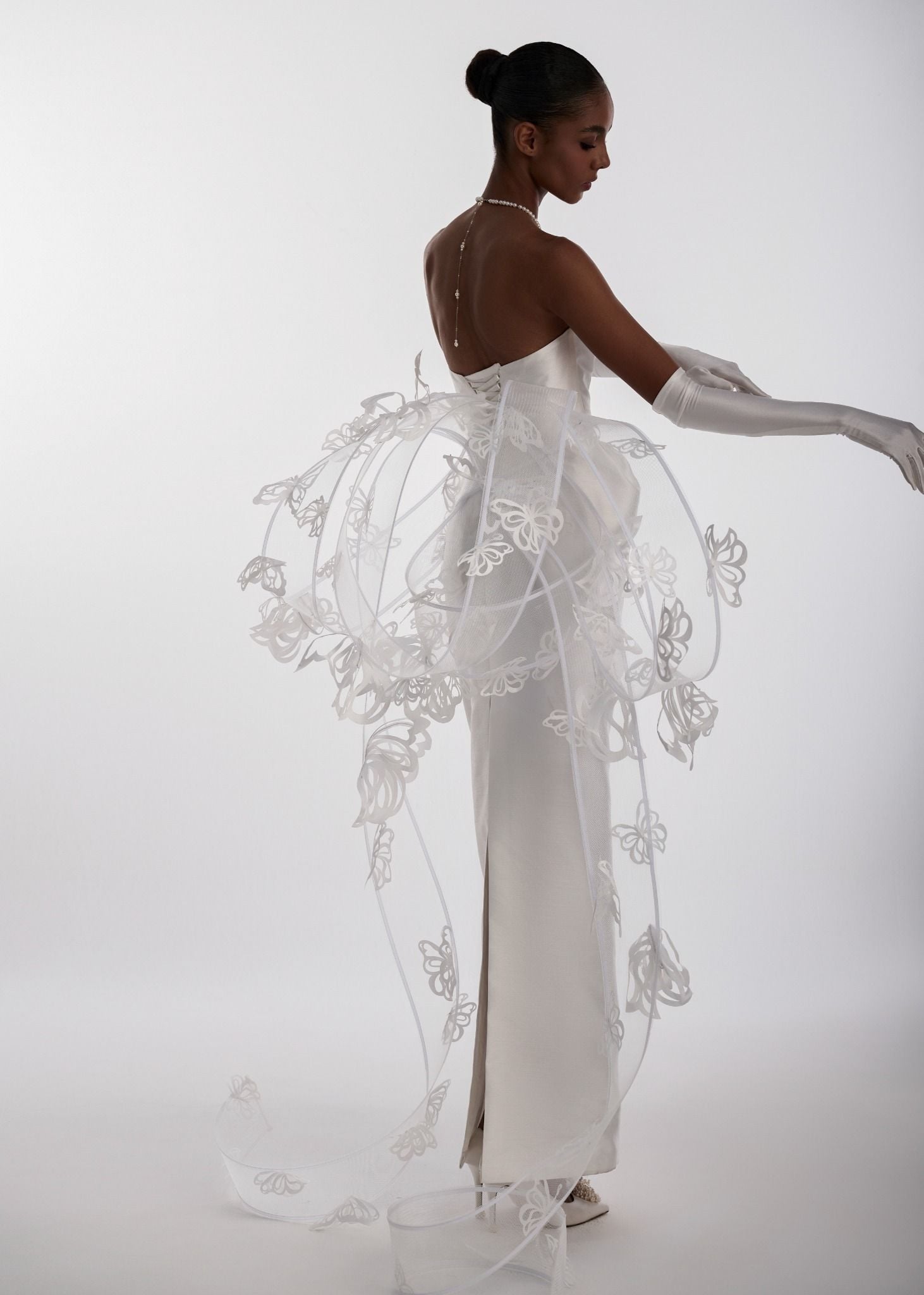 Woman in a white wedding dress with intricate detailing on a white background